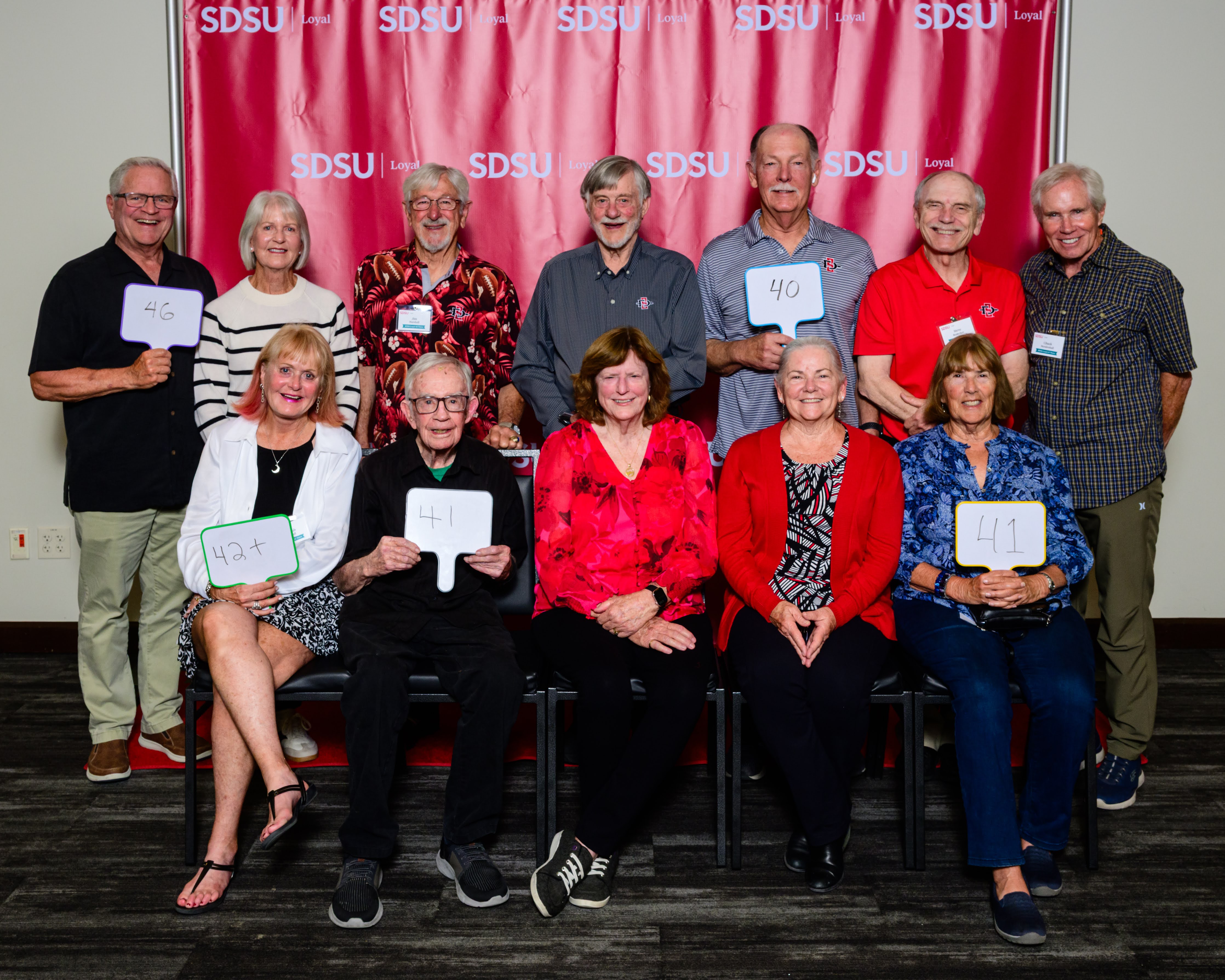 a group of people in front of an SDSU backdrop
